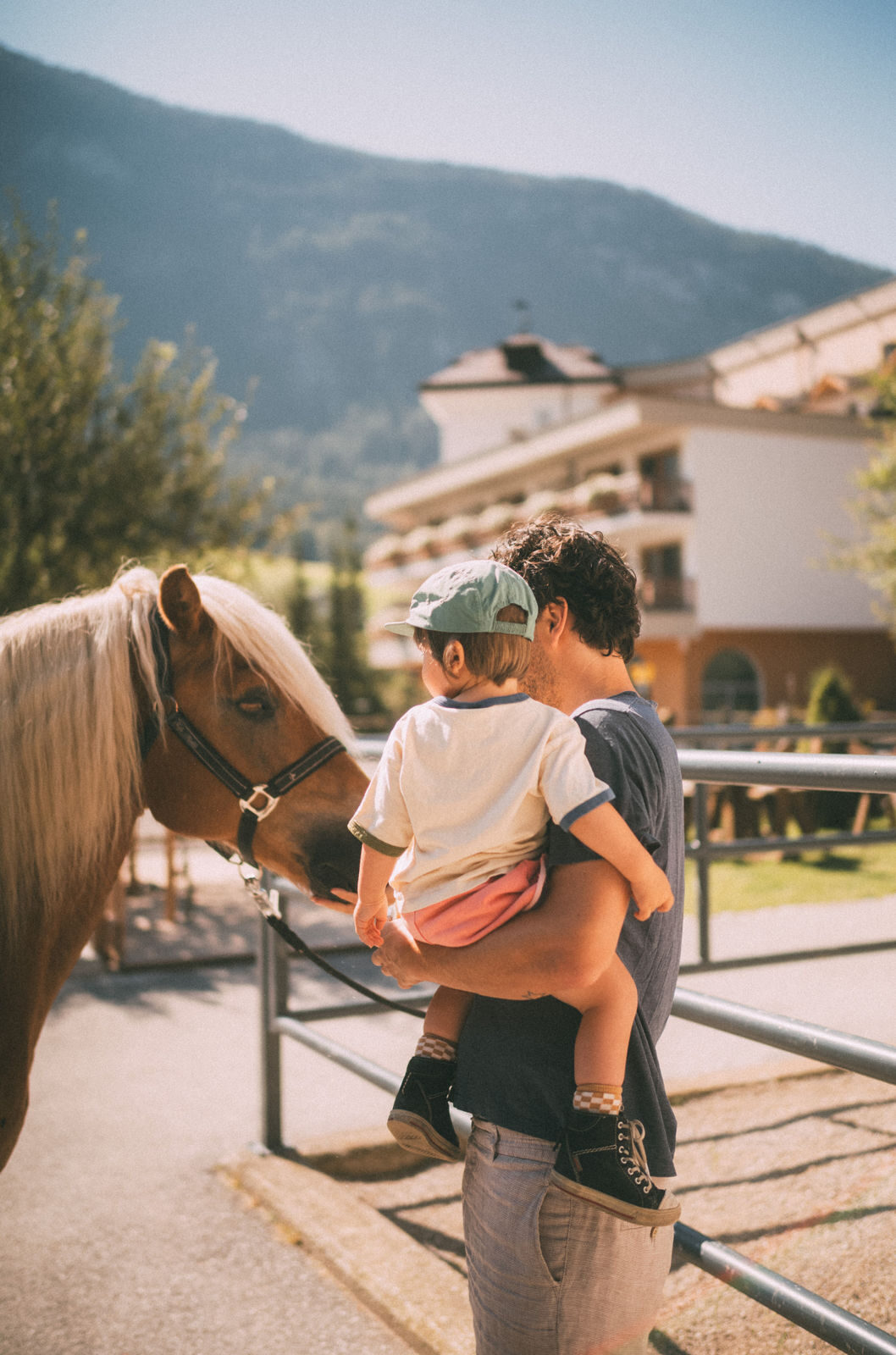 Father and son meet a pony, the POST hotel in the warm afternoon light behind.