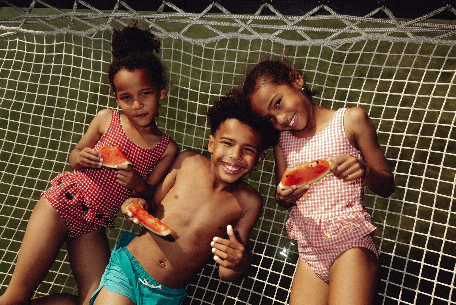 A family lying on a hammock at midday, sun out.