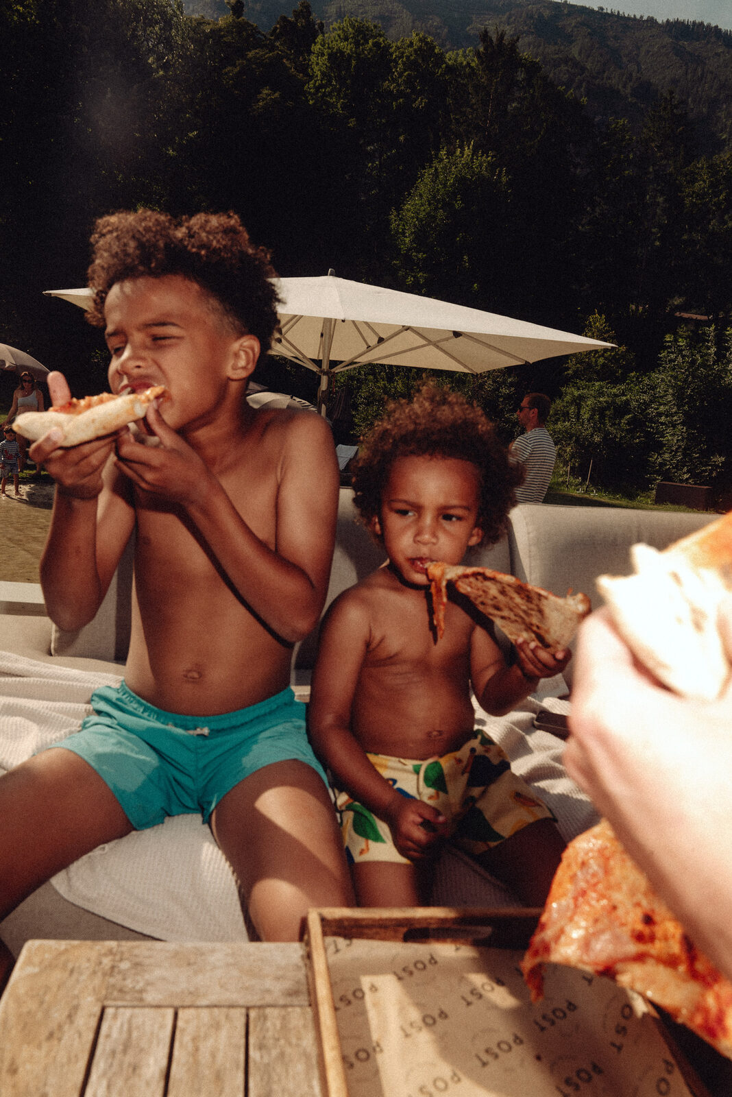 Children eating pizza outdoors, late afternoon.