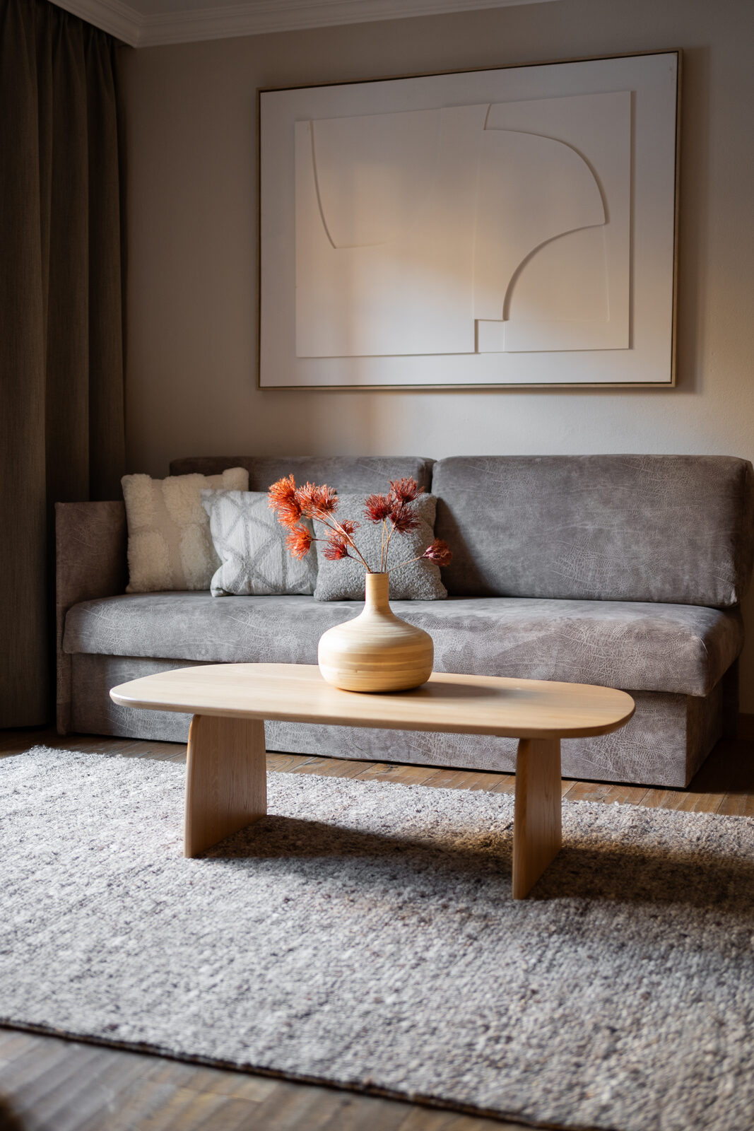 Living area in a 3-room suite, gray sofa under a contemporary line drawing.