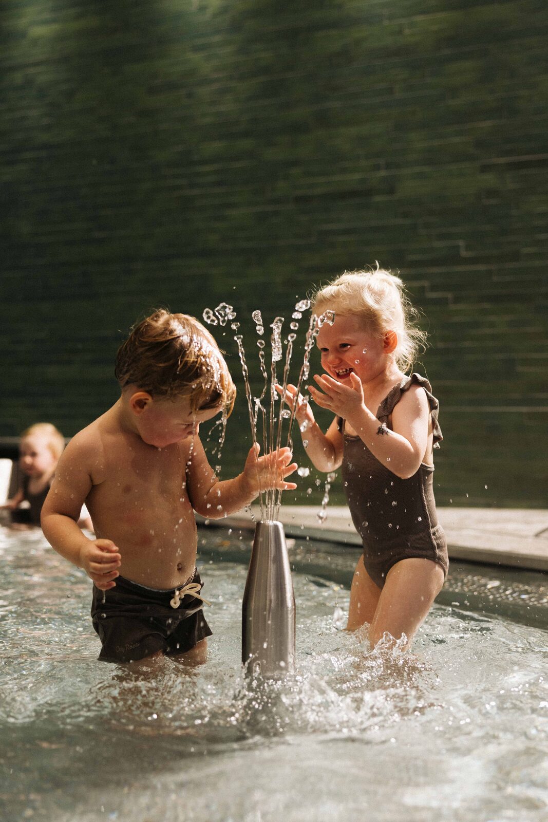 Two toddlers play in a fountain in the family pool at POST.