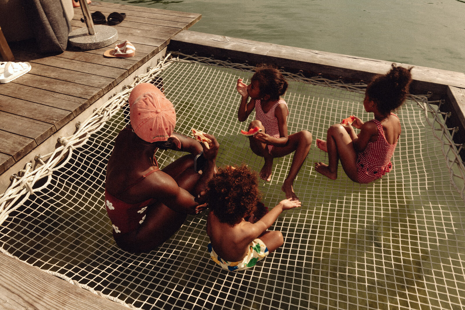 Children eat watermelon on the lake's floating net.
